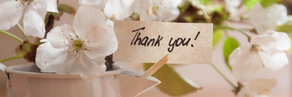 Karte mit der Aufschrift „Thank you!“ zwischen weißen Blüten